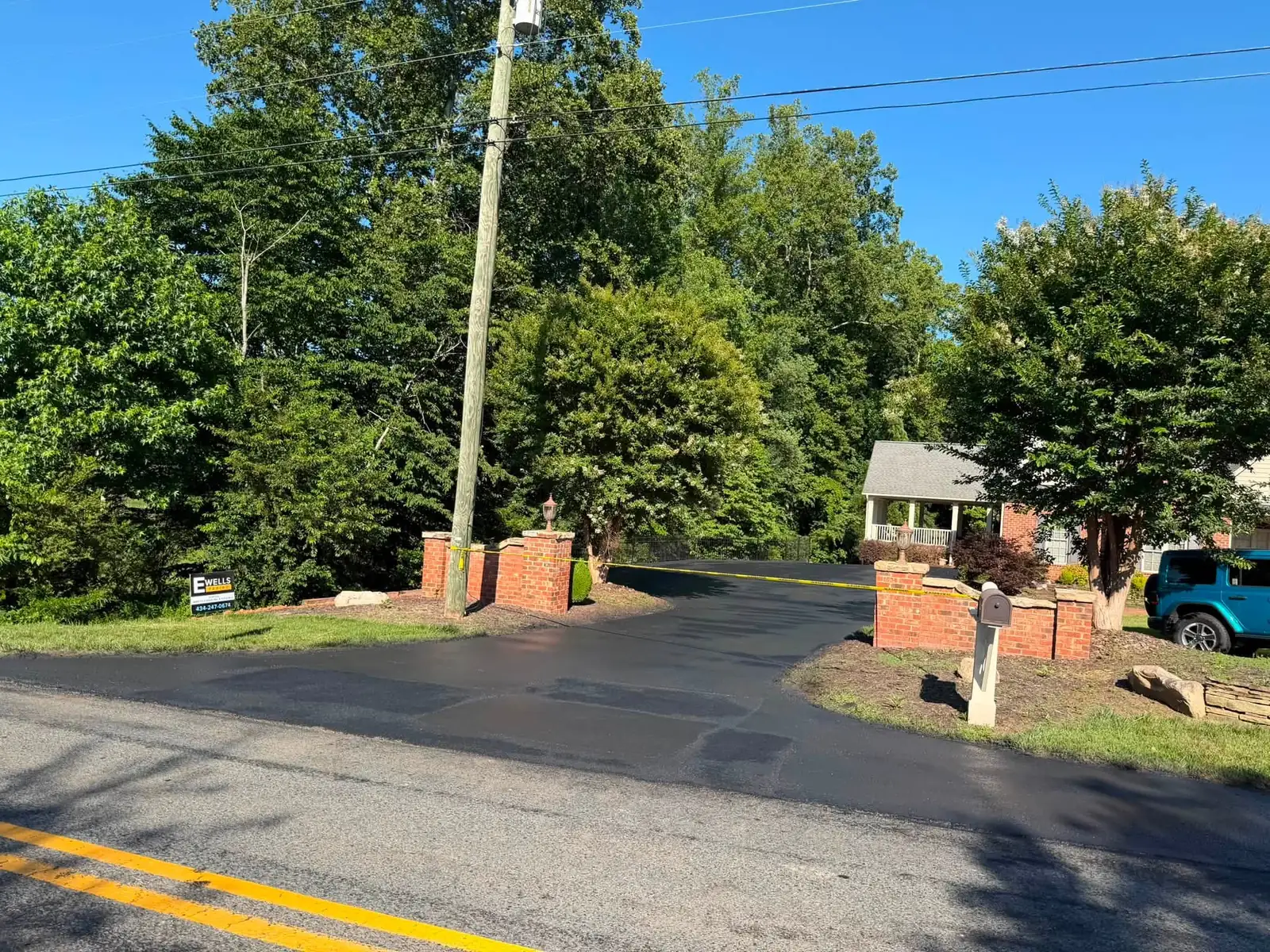Finished dark driveway between the same brick entry pillars