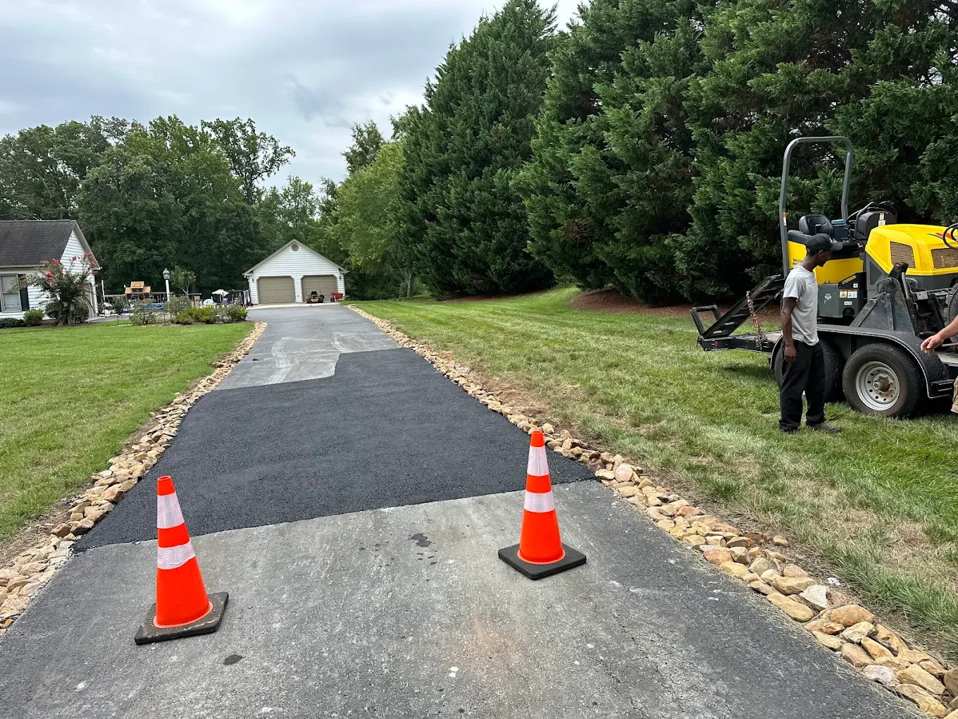 Asphalt patches and safety cones on a long residential driveway